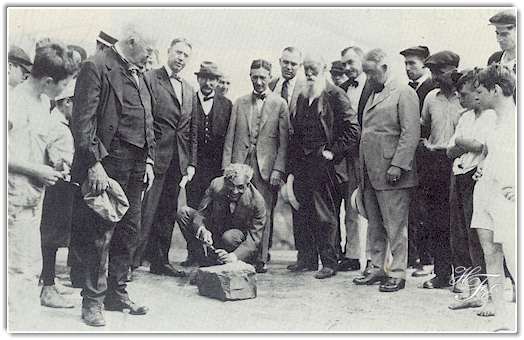 This photo was taken on August 5, 1919 during the vagabonds' camping trip, and shows Henry Ford carving his initials on the stone which became the cornerstone of his manufacturing plant at Green Island, New York, which to this day is the key plant of Ford's Engine and Foundry Division. Others in the picture include Thomas A. Edison, holding cap; Harvey Firestone, standing behind Mr. Ford; John Burroughs, the bearded naturalist and writer, on Mr. Firestone's left; Cornelius Burns, then mayor of Troy, N.Y ., in which the plant is located, on Mr. Firestone's left; and James R. Watt, then mayor of Albany, standing between Messrs. Edison and Ford. Photo from Ford's Green Island Plant.